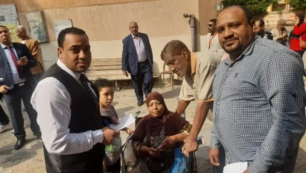 قاضي يخرج من لجنته لمساعدة سيدة على كرسى متحرك